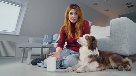 Finanzexpertin Aya Jaff sitzt mit Hund vor einem Sofa. © NDR/i&u Tv 