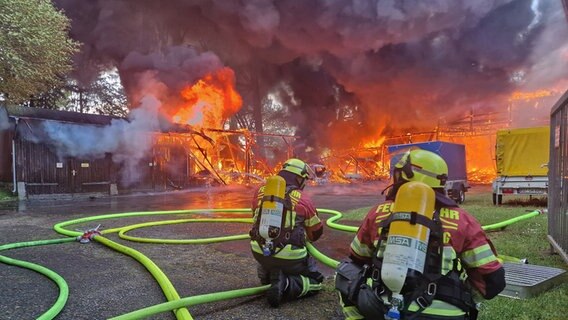 Einsatzkräfte der Feuerwehr hocken vor einem brennenden Gebäude. © Kreisfeuerwehrverband Rendsburg-Eckernförde 