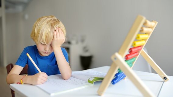 ADHS bei Kindern: Ein Kind sitzt unglücklich über den Hausaufgaben © colourbox.de 